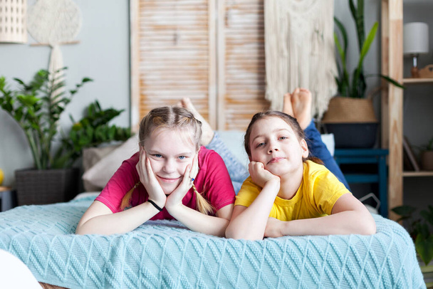 Két tinédzser lánytestvér portréja otthon az ágyon..  - Fotó, kép
