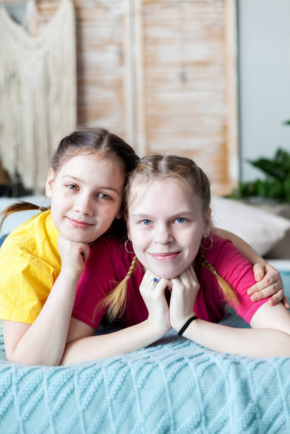 Портрет двух сестер-подростков на кровати дома
.  - Фото, изображение