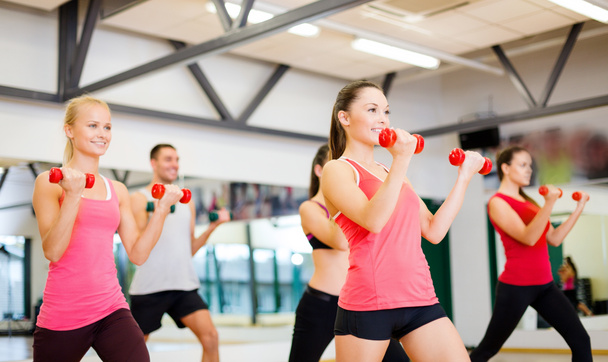 Group of smiling people working out with dumbbells - Photo, Image