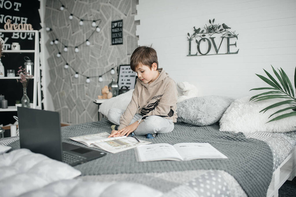 Мальчик учится дома с книгами и компьютером
 - Фото, изображение