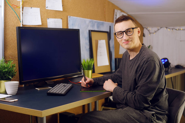 Muž pracuje doma s tabulkou a perem. Griffine návrháři, muž se podívá na zelený obrazovkový počítač. Člověk pracuje na volné noze, učí se nové technologie, distanční vzdělávání. - Fotografie, Obrázek