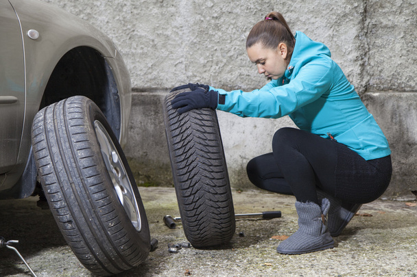 Pretty girl replacing car tyre - Photo, Image