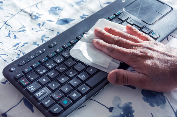 Ανδρικό ασιατικό χέρι καθαρισμού φορητό πληκτρολόγιο με αντιβακτηριακά μαντηλάκια κατά τη διάρκεια καραντίνας, Σουηδία - Φωτογραφία, εικόνα