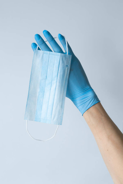 First person view of a woman holding face mask over white table background. Protective raspiratory mask for spreading virus. Close up, copy space, top view, flat lay - Zdjęcie, obraz