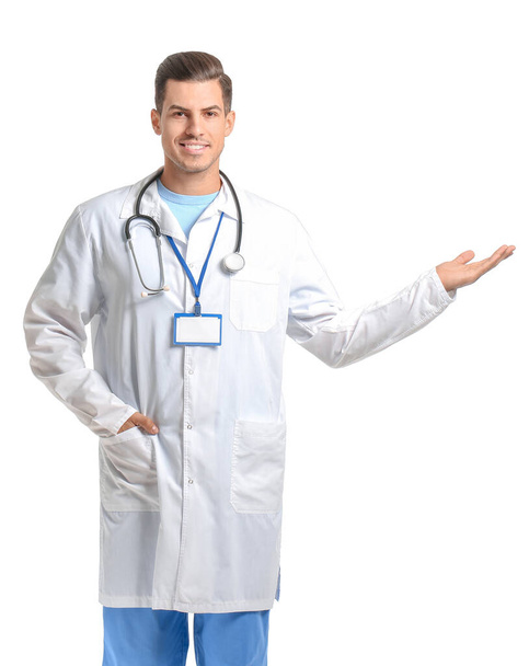Πορτρέτο του νεαρού άνδρα γιατρό δείχνει κάτι σε λευκό φόντο - Φωτογραφία, εικόνα