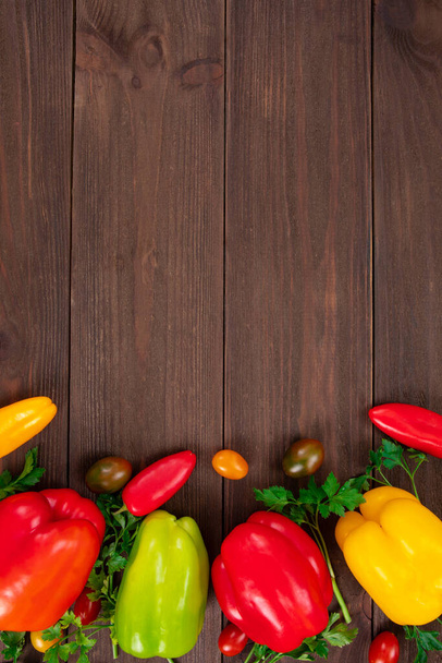 Vista superior de vegetais coloridos frescos, como pimentão, tomate cereja e folhas de salsa no fundo de madeira. Alimentos orgânicos saudáveis
 - Foto, Imagem