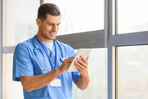 Portrait of young male doctor with tablet computer near window - Photo, Image