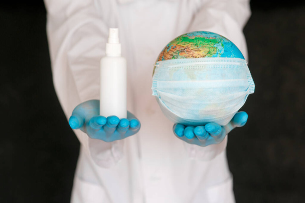 The concept is to protect the planet from coronavirus. splash the antiseptic on the globe. Covid-19 and the globe in the hands of the doctor - Foto, afbeelding