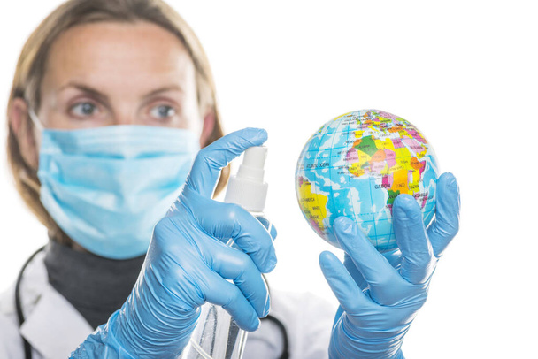 Young female doctor treats globe with an antiseptic to protect hands from coronavirus virus. Healthcare concept. COVID-19 Coronavirus pandemic. - Fotografie, Obrázek