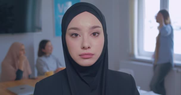 Close-up portrait of a young beautiful sad Caucasian girl in hijab office background - Video