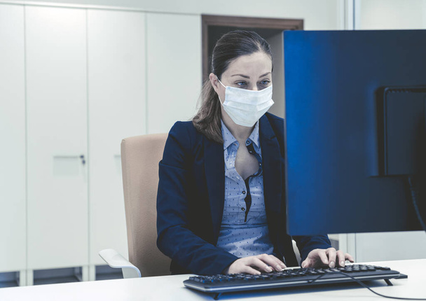 бізнесмен працює на ноутбуці в офісі з хірургічною маскою
 - Фото, зображення