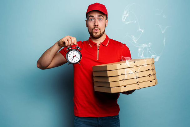 Courier is punctual to deliver quickly pizzas. Cyan background - Foto, afbeelding