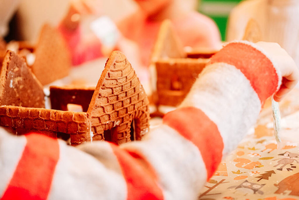 Lebkuchenbacken, ein Haus mit Plätzchen für den Weihnachtsmann, Kinder bereiten sich auf das Essen vor, dekorieren das Haus - Foto, Bild