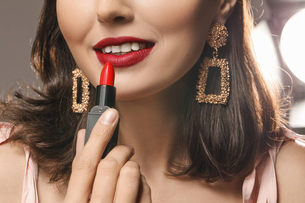 Beautiful young woman applying makeup against grey background, closeup - Photo, Image