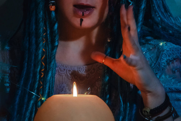 Девушка с голубыми дредами ночью в тёмной комнате, огнём свечи и коровьим черепом
 - Фото, изображение