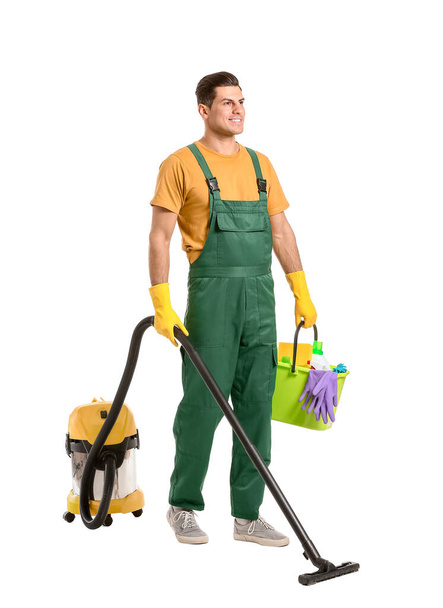 Young man with vacuum cleaner and supplies on white background - Photo, Image