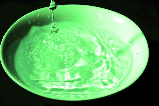 Drop of water on white bowl, green, black background - Photo, Image
