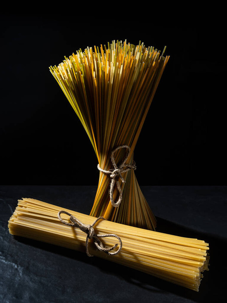 Harde pasta gemaakt van tarwebloem, typisch Italiaanse gerechten, met een grote calorische waarde en een hoog gehalte aan snel absorberende koolhydraten. - Foto, afbeelding