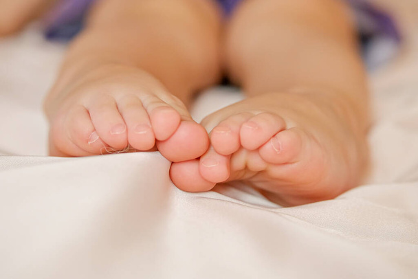 legs of a small child, the baby is sitting on a crib in a bright room. warmth and tranquility - Foto, Imagem