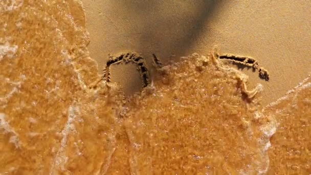 Palabra AMOR pintado en la arena es lavado por la ola
 - Metraje, vídeo