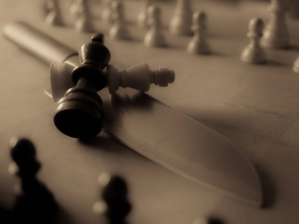 Šachové figurky a kuchyňský nůž. Strategická hra. To se hraje na 64 čtverečních černé a bílé desky. - Fotografie, Obrázek