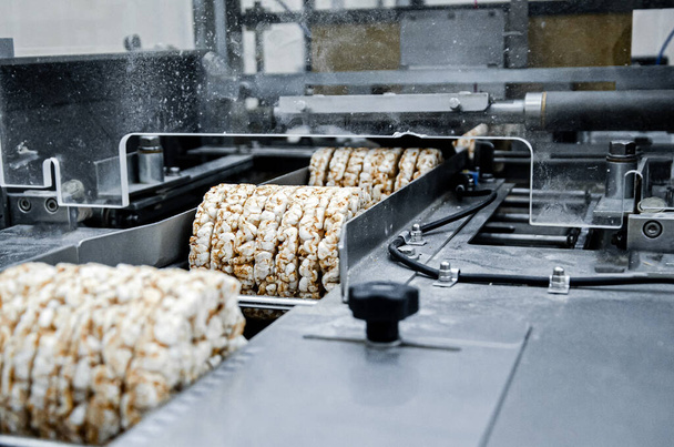 有用な全粒押出機クリスピーパンの生産のためのコンベア自動テープ。工場で有機多大麦のブリキッとしたパンを梱包し - 写真・画像