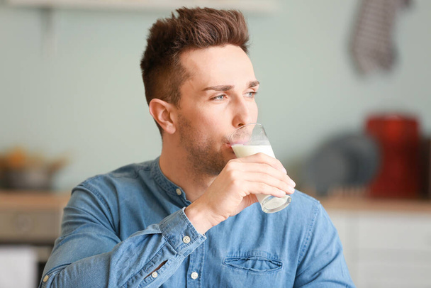 Young man drinking milk in kitchen - Foto, immagini