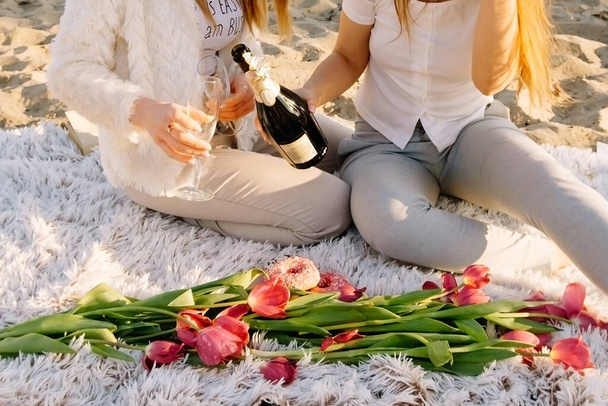 hermosa chica se sienta en un cuadros con un ramo de tulipanes. Desayuno romántico al amanecer con el sol
. - Foto, imagen