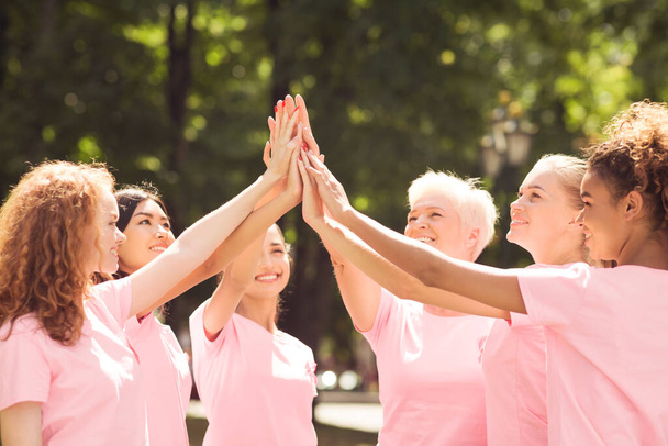 Pacientky s karcinomem prsu v růžových tričkách dávají vysoké pět venku - Fotografie, Obrázek