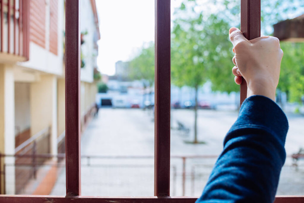 a woman's hand grabbing the bars of a window. - Foto, immagini