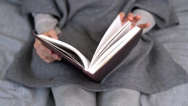 Chica caucásica con cabello rubio leyendo un libro. Adolescente joven aprendiendo en la escuela en casa en cuarentena. - Imágenes, Vídeo