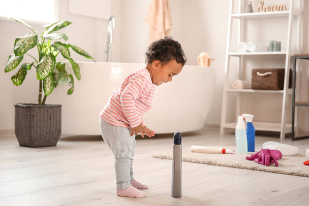 Kleine Afro-Amerikaanse baby spelen met wassen vloeistoffen thuis. Kind in gevaar - Foto, afbeelding