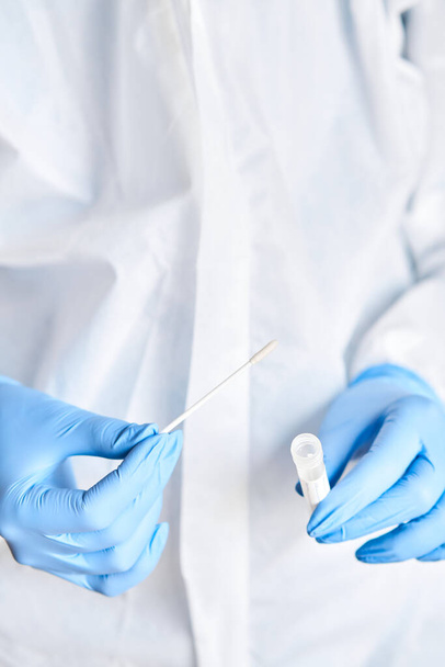 Arzt hält Tupfer Reagenzglas für 2019-nCoV-Analyse. Coronavirus-Test. Blaue medizinische Handschuhe und Mundschutz zum Schutz vor Covid-19-Virus. Coronavirus und Pandemie. - Foto, Bild