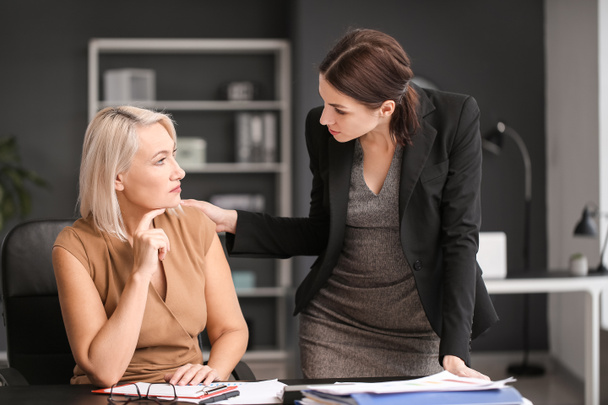 Woman calming her fired mature colleague in office - 写真・画像