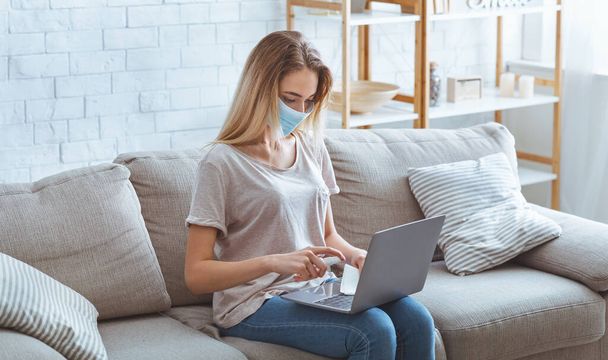 Menina em máscara desinfecta laptop com anti-séptico
 - Foto, Imagem