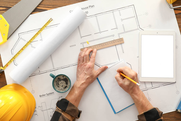 Mannelijke bouwer werken met huis plan, top view - Foto, afbeelding