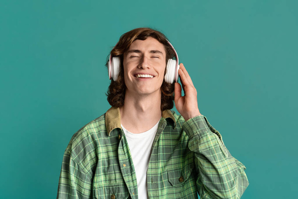 Funky chico con los ojos cerrados disfrutando de su música favorita en los auriculares, fondo de color
 - Foto, imagen