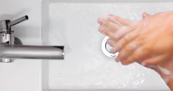 Vista superior de um homem lavando as mãos com sabão espumoso em uma bacia de lavagem branca
 - Filmagem, Vídeo
