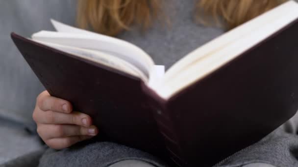 Chica caucásica con cabello rubio leyendo un libro. Adolescente joven aprendiendo en la escuela en casa en cuarentena. - Metraje, vídeo