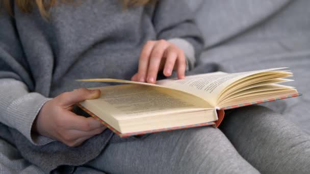 Fille blanche aux cheveux blonds lisant un livre. Jeune adolescent apprenant à l'école à domicile en quarantaine. - Séquence, vidéo