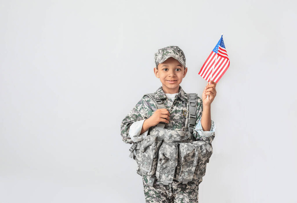 Kleine Afro-Amerikaanse soldaat met USA vlag op lichte achtergrond - Foto, afbeelding