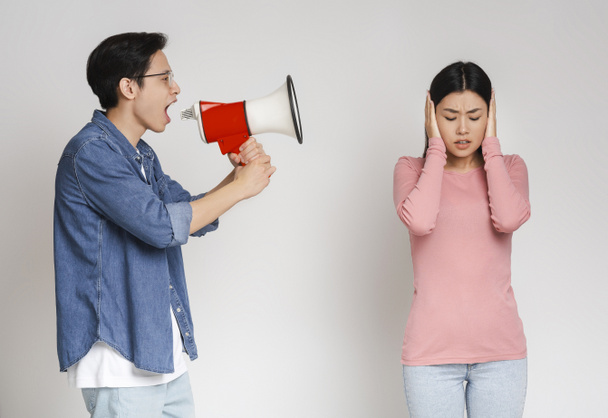 Boos aziatische man schreeuwen door megafoon naar zijn vriendin - Foto, afbeelding