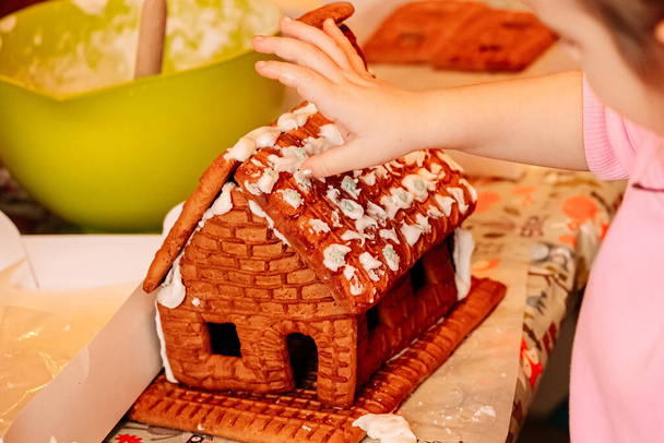 cooking gingerbread cookies, a house of cookies for Santa, kids are preparing to eat, decorating the house - Foto, afbeelding