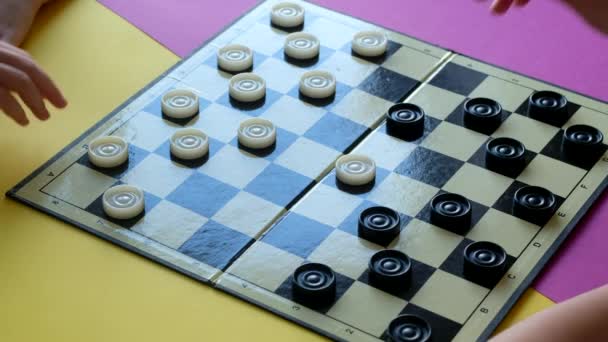 Children play checkers on a colorful table. Boy and girl compete in board games. - Footage, Video