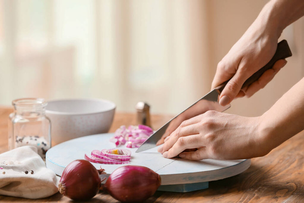 Mujer cortando cebolla cruda fresca en la cocina, primer plano
 - Foto, imagen