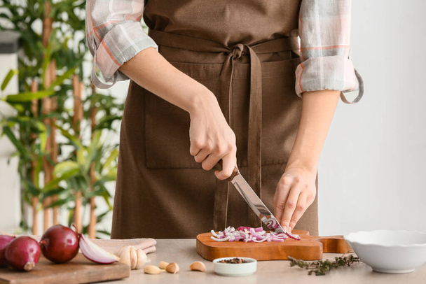 Nainen leikkaa tuoretta raakaa sipulia keittiössä, lähikuva
 - Valokuva, kuva