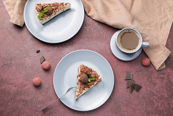 Platen met stukjes smakelijke chocolade cheesecake en kopje koffie op kleur achtergrond - Foto, afbeelding