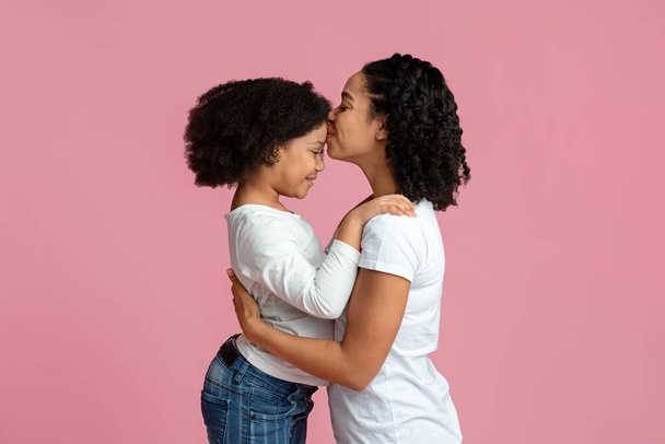 Szerető anya. Boldog fekete nő csókolgatja imádnivaló kislányait Homlok - Fotó, kép