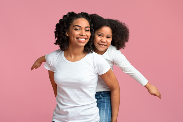 Usmívající se africká americká matka nesoucí její roztomilé dcerušky na zádech - Fotografie, Obrázek