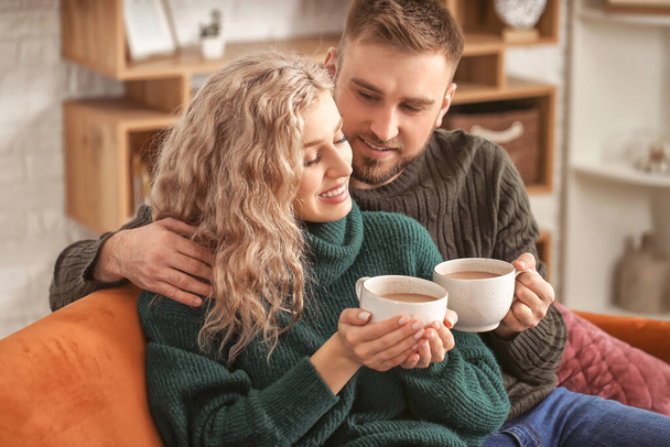 Feliz joven pareja bebiendo cacao caliente en casa
 - Foto, imagen